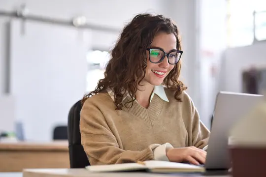 Junge Auszubildende sitzt am Schreibtisch mit Laptop
